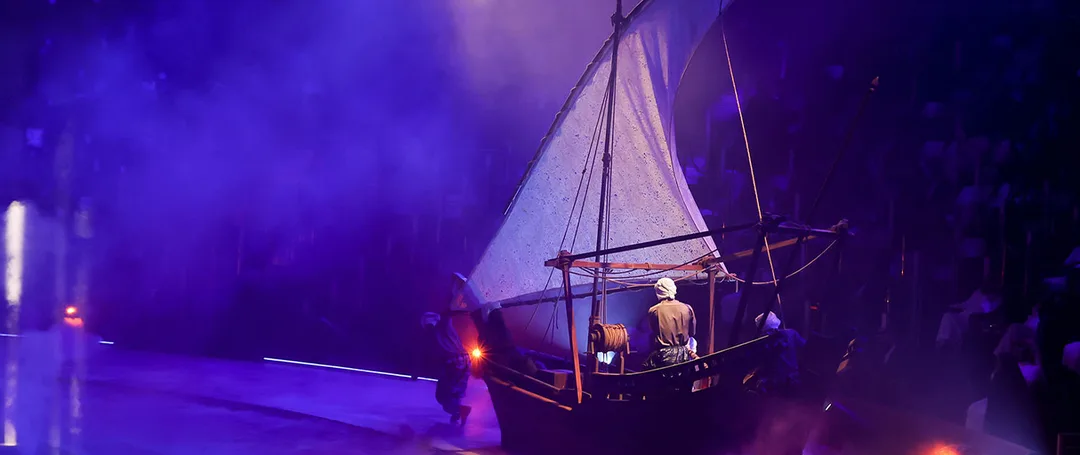 Terhal land-abra scenic boat moving through the live performance under theatrical lighting in Riyadh.