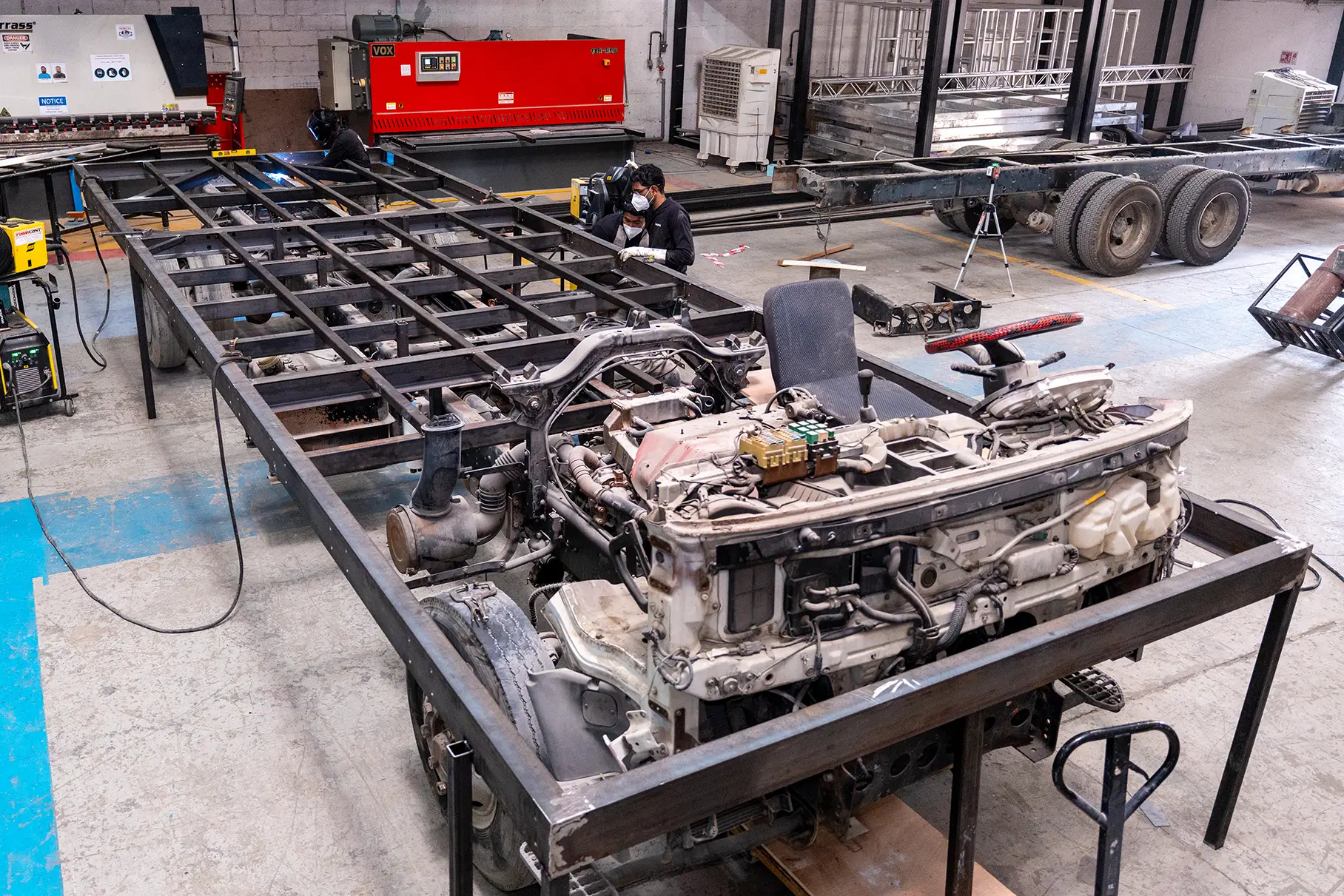 Vehicle chassis beside fabricated scenic subframe during early integration
