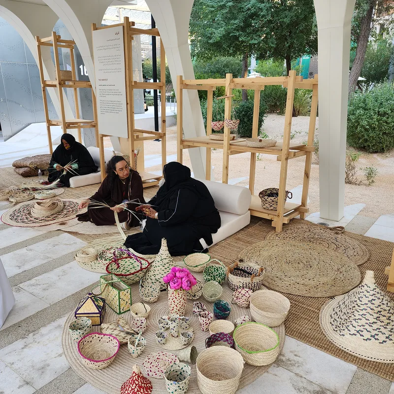 Evolution Scenic open-frame display structures supporting traditional date-palm weaving demonstrations.